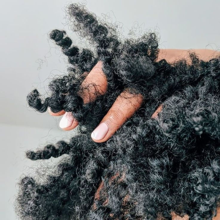 Main de Yannick montrant la texture de ses cheveux naturels aux multiples textures